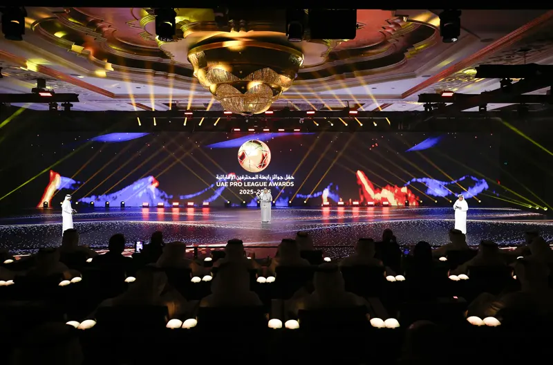 Wide shot of the ballroom — tribunes around the LED floor pitch